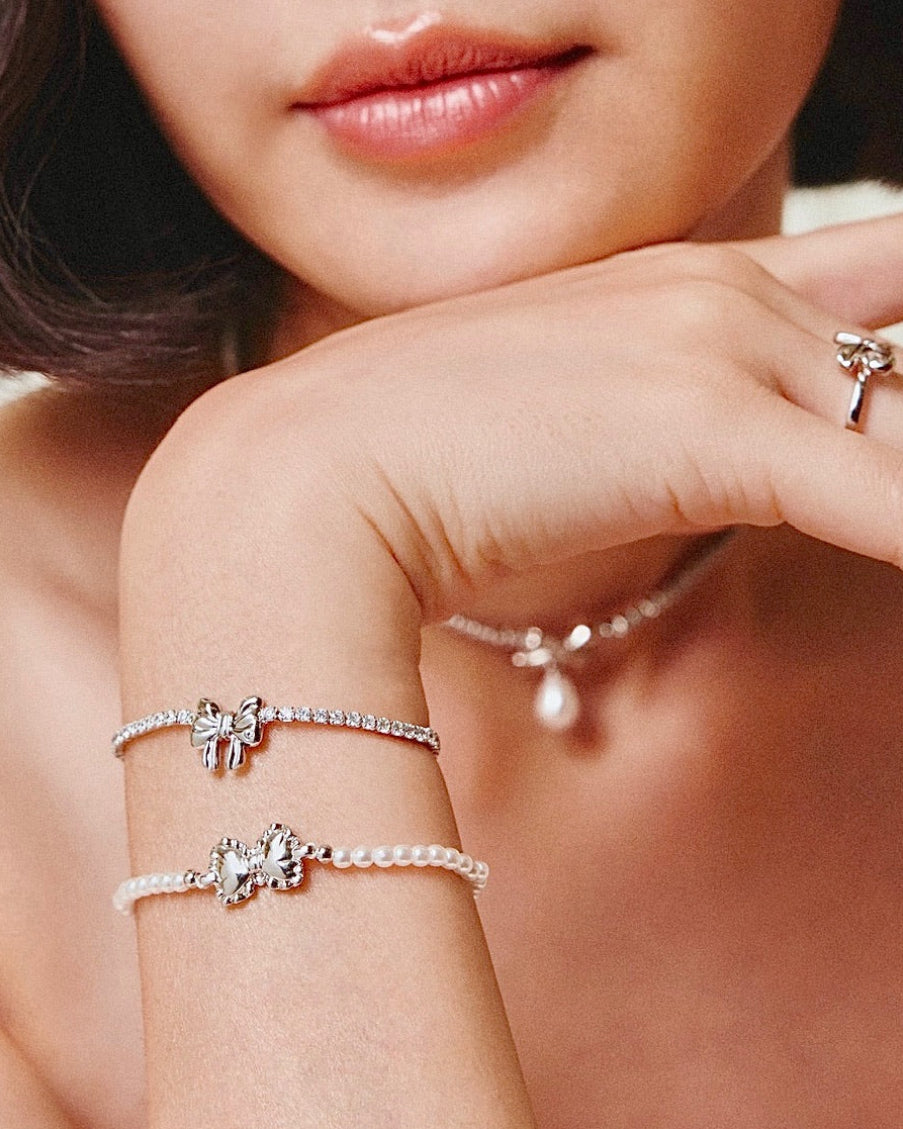 Close-up of a woman's arm wearing silver bracelets with decorative elements.